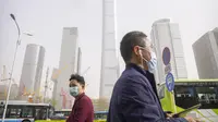 Para komuter yang mengenakan masker berjalan saat badai debu dan pasir di kawasan pusat bisnis di Ibu Kota Beijing, China, Selasa (11/4/2023). Serangkaian badai debu dan pasir terbaru membuat indeks kualitas udara memburuk di Beijing pada Senin malam hingga Selasa. (AP Photo/Mark Schiefelbein)