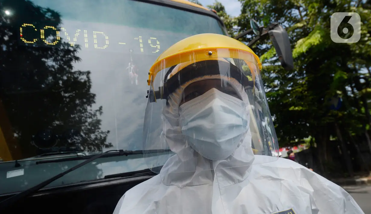Petugas Dishub memakai baju APD akan menjemput korban yang diduga terjangkit Covid-19 menggunakan bus sekolah di Puskesmas Kebayuran Lama, Jakarta, Senin (6/7/2020). Bus sekolah tersebut selama liburan dibantukan untuk mengangkut pasien Covid-19 ke Wisma Atlet Kemayoran. (merdeka.com/Dwi Narwoko)