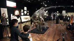 Anak-anak melihat kerangka dinosaurus Allosaurus di rumah lelang Drouot, Paris, Prancis, Sabtu (10/10/2020). Kerangka dinosaurus yang ditemukan di daerah Johnson, Wyoming, AS, tersebut akan dilelang pada 13 Oktober 2020 dan diperkirakan harganya antara 1-1,2 juta euro. (AP Photo/Thibault Camus)