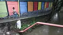 Warga melintas dekat tembok warna-warni di Kampung Penas Tanggul, Cipinang Besar Selatan, Jakarta, Kamis (23/3). Kampung warna-warni tanpa rokok itu dibuat warga sebagai bentuk upaya perlindungan bagi perempuan dan anak. (Liputan6.com/Immanuel Antonius)