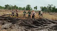 Polisi dan TNI mendinginkan lokasi kebakaran lahan di Rokan Hilir. (Liputan6.com/M Syukur)