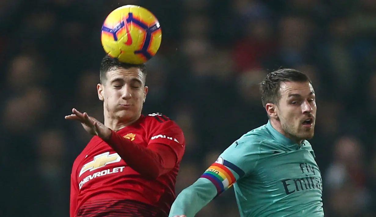 Bek Manchester United, Diogo Dalot berebut bola udara dengan gelandang Arsenal, Aaron Ramsey selama pertandingan lanjutan Liga Inggris di stadion Old Trafford (5/12). MU bermain imbang 2-2 atas Arsenal. (AP Photo/Dave Thompson)