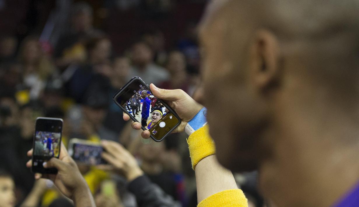 Fans melakukan foto selfie bersama Pemain Los Angels Lakers, Kobe Bryant #24 usai bertanding melawan Philadelphia 76ers pada laga NBA di Wells Fargo Center, Philadelphia, Pennsylvania, Selasa (1/12/2015).  (AFP Photo/Mitchell Leff/Getty Images/AFP)