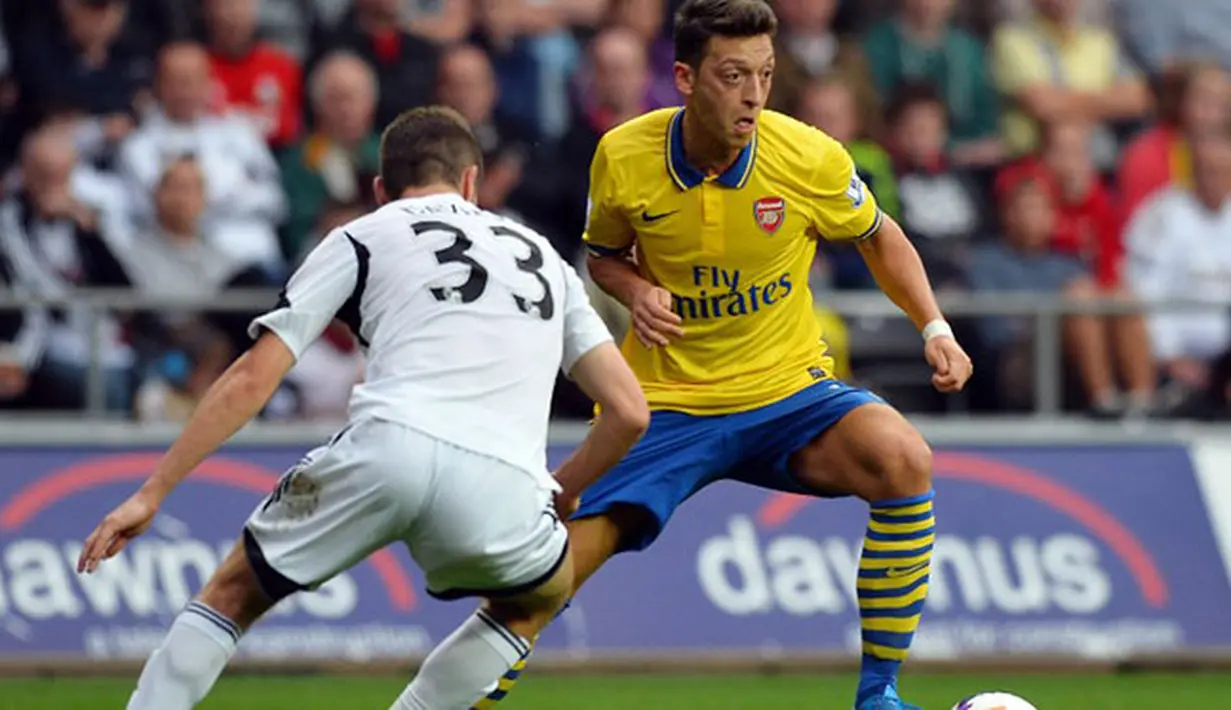 Pemain Arsenal Mesut Ozil dihadang Pemain Swansea City Ben Davies Pada pertandingan Liga Premier Inggris antara Swansea City dan Arsenal di Stadion Liberty di Swansea (28/09/13). (AFP/Paul Ellis)