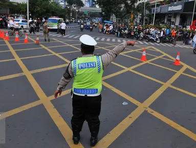Seorang petugas polisi mengalihkan arus di kawasan Sarinah, Jakarta, Jumat (4/11). Pengalihan ini dilakukan karena aksi 4 November yang memadati tiga titik, yaitu di kantor Bareskrim Polri Balai Kota DKI, dan Istana Negara. (Liputan6.com/Angga Yuniar)