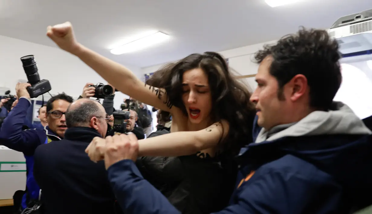 Petugas keamanan membawa seorang aktivis Femen karena telah bertelanjang dada atau topless di hadapan mantan PM Italia dan pemimpin partai Forza Italia Silvio Berlusconi di Milan, Italia, Minggu (4/3). (AP Photo/Luca Bruno)