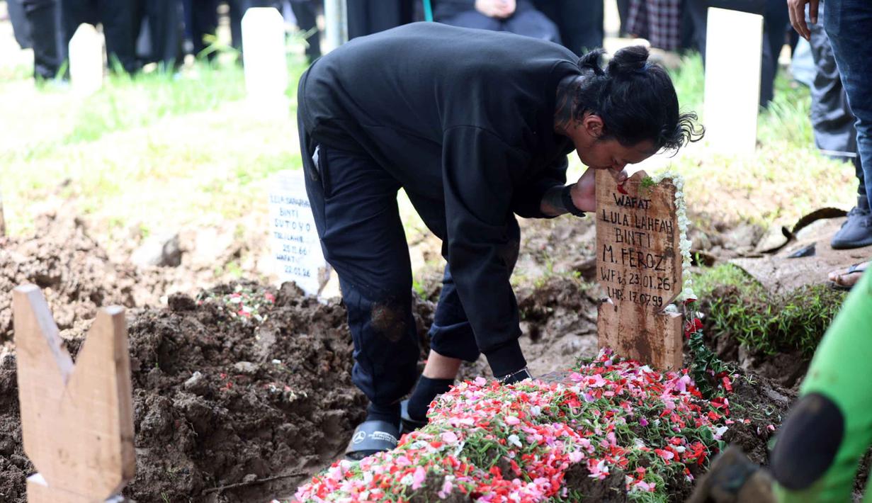 Sebelumnya diberitakan, Lula Lahfah ditemukan meninggal dunia di kamarnya di sebuah apartemen di Jakarta Selatan pada Jumat (23/1/2026) petang. Tampak dalam foto, konten kreator yang juga musisi, Reza Oktovian atau lebih dikenal dengan panggilan Reza Arap mencium nisan kekasihnya, Lula Lahfah, di Tempat Pemakaman Umum (TPU) Rawa Terate, Cakung, Jakarta Timur, pada Sabtu (24/1/2026). (Kapanlagi.com/Budy Santoso)