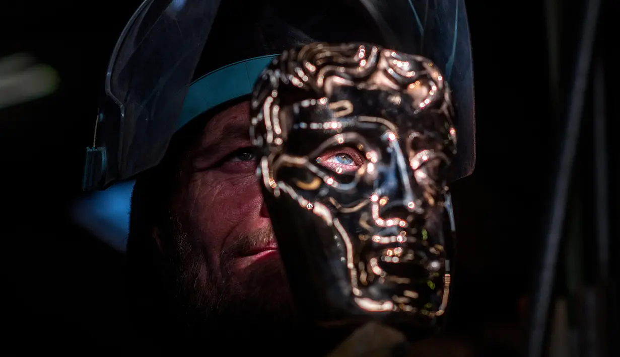 Fettler Piotr Lichon membuat topeng BAFTA (British Academy of Film and Television Arts) mask di New Pro Foundries, London, pada 21 Januari 2020. (JUSTIN TALLIS / AFP)