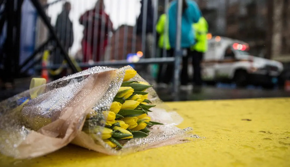 Seikat bunga diletakan di garis finish Boston Marathon pada peringatan setahun terjadinya Bom Boston, Selasa (15/4/14) (AFP/Andrew Burton)