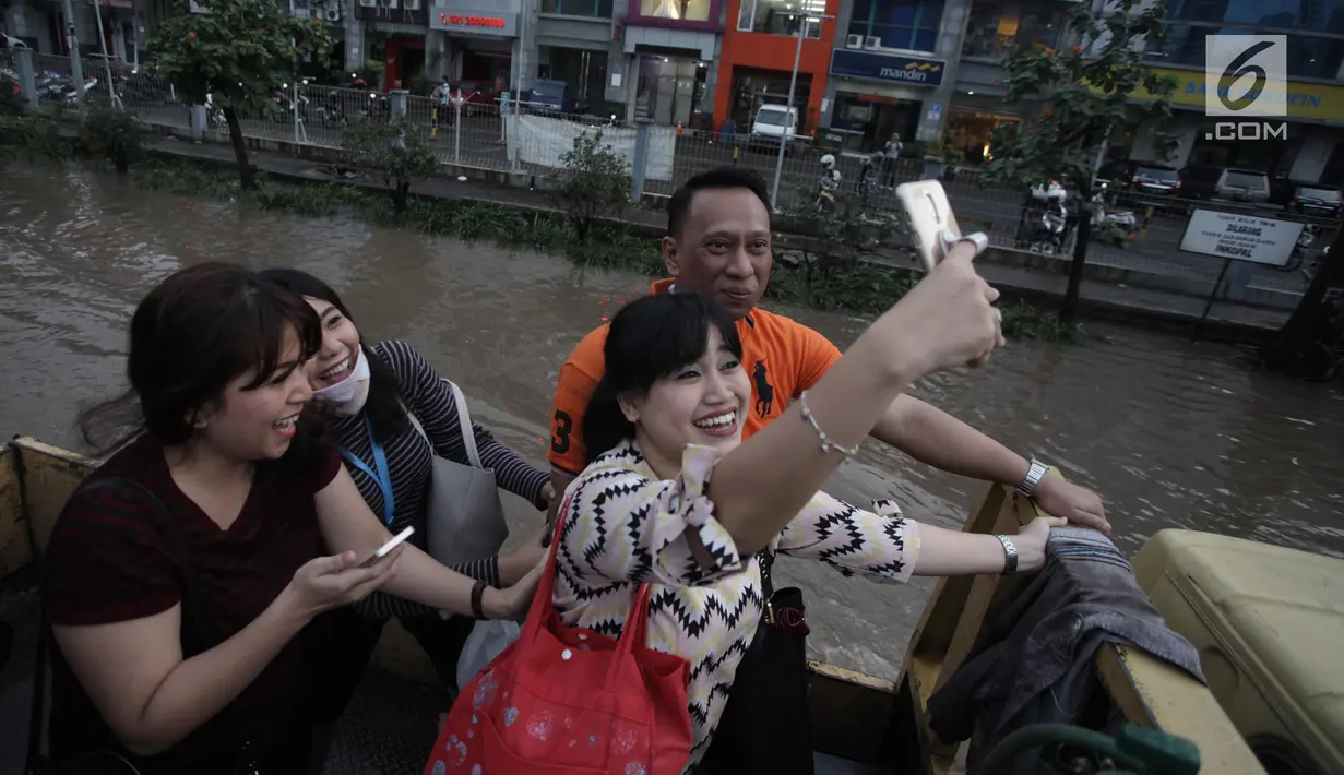 Warga berswafoto di atas truk terbuka ketika banjir merendam di Jalan Boulevard Raya, Kelapa Gading, Jakarta, Kamis (15/2). Hujan yang mengguyur Jakarta mengakibatkan kawasan Kelapa Gading terendam banjir. (Liputan6.com/Arya Manggala)
