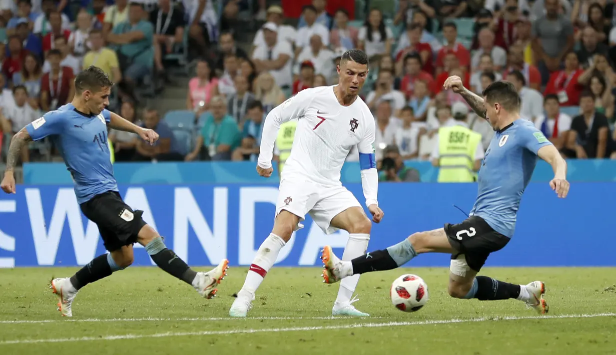 Cristiano Ronaldo berusaha melewati adangan dua pemain Uruguay pada laga 16 besar Piala Dunia 2018 di Fisht Stadium, Sochi, Rusia, (30/6/2018). Portugal kalah 1-2 dari Uruguay. (AP/Francisco Seco)