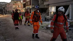 Anggota tim penyelamat Inggris melihat-lihat bangunan yang hancur di Antakya, Turki, 9 Februari 2023. Tim penyelamat melakukan upaya terakhir pada Kamis untuk menemukan korban selamat dari bencana gempa bumi di Turki dan Suriah yang membuat banyak komunitas tidak dapat dikenali oleh penghuninya. (AP Photo/Khalil Hamra)