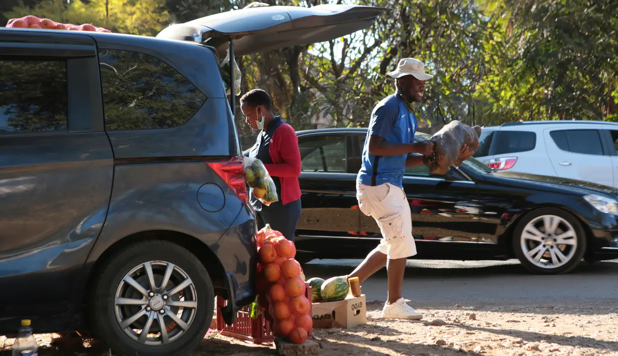 Seorang pria membawa sekantong kentang untuk pelanggan saat berjualan dari mobilnya di Harare, 23 Juni 2020. Mobil menjadi pasar bergerak di mana penduduk Zimbabwe menjual barang dagangan dari kendaraan untuk mengatasi kesulitan ekonomi yang disebabkan Covid-19. (AP Photo/Tsvangirayi Mukwazhi)