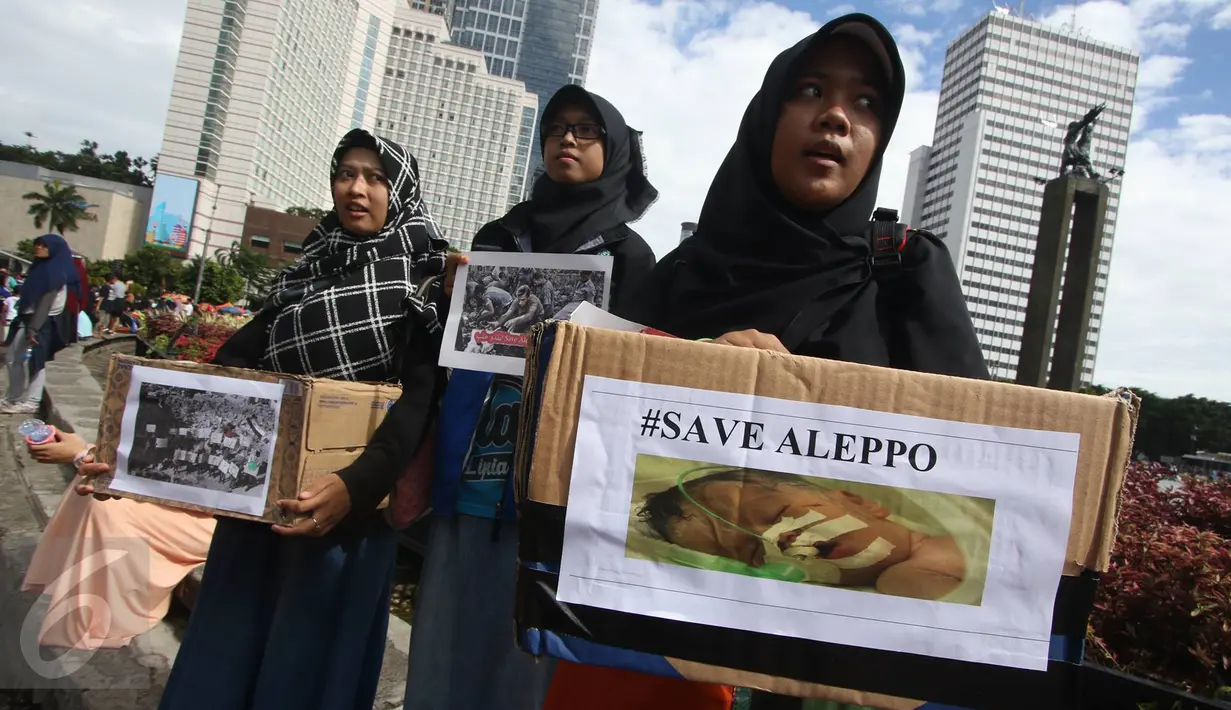 Massa membawa foto korban pemboman dan penghancuran Kota Aleppo, Suriah saat menggelar aksi solidaritas save Aleppo di kawasan Bundaran HI, Jakarta, Minggu (18/12). Aksi ini diwarnai berbagai orasi dan penggalangan dana. (Liputan6.com/Immanuel Antonius)
