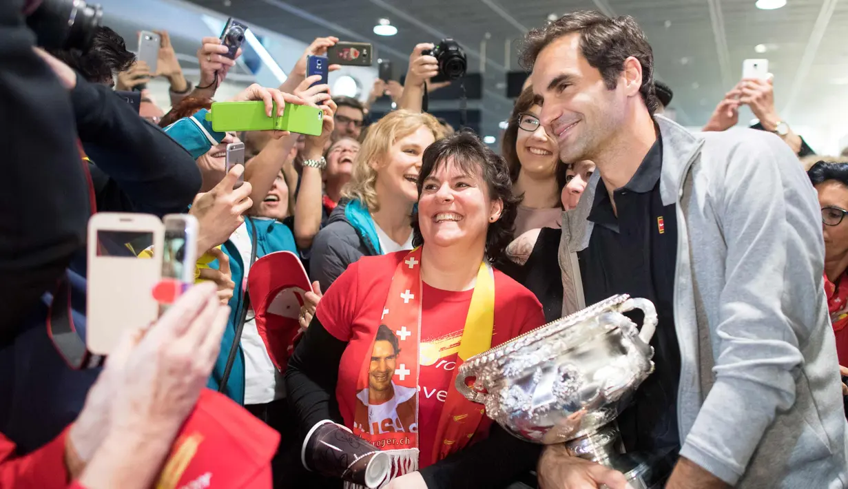 Penggemar wanita berpose dengan Roger Federer yang membawa trofi Australia Terbuka 2018 di Bandara Zurich, di Kloten, Swiss, (30/1). Federer memenangkan final tunggal putramelawan petenis Kroasia Marin Cilic. (Ennio Leanza/Keystone via AP)
