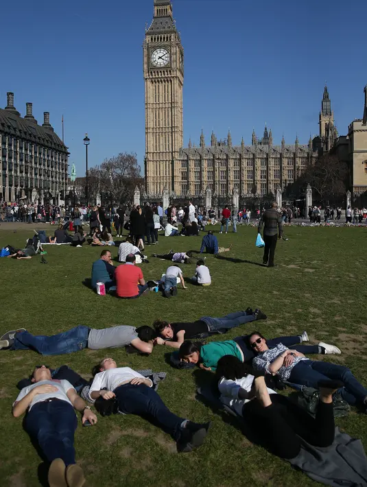 Sejumlah orang bersantai di bawah sinar matahari di Parliament Square di pusat kota London Inggris, Sabtu (8/4). (AFP PHOTO / Daniel Leal-Olivas)