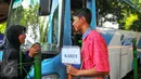 Warga bertanya kepada petugas feeder bus Transjakarta yang sedang ngetem di seberang Stasiun Tebet , Jakarta, Kamis (7/4). Armada itu dikerahkan untuk mengantisipasi penumpukan penumpang saat perlintasan KRL Tebet ditutup. (Liputan6.com/Yoppy Renato)