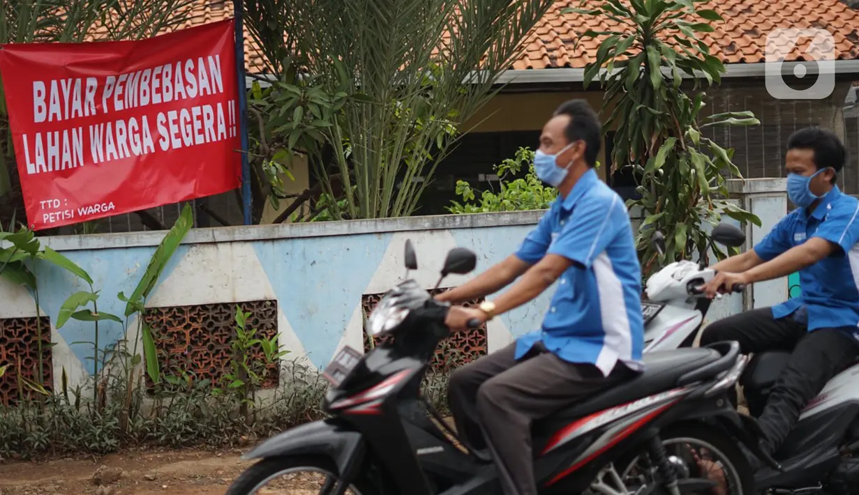 Pengendara motor melintas di depan poster protes warga terhadap pembangunan flyover di kawasan Tanjung Barat, Jakarta, Rabu (15/7/2020). Dalam poster protes tersebut, warga menuntut agar pembayaran pelunasan pembebasan lahan segera diselesaikan secara serentak. (Liputan6.com/Immanuel Antonius)