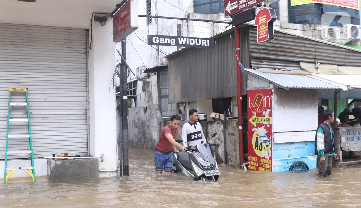 Warga mendorong motor saat banjir merendam kawasan Benhil, Jakarta, Selasa (25/2/2020). Hujan yang mengguyur wilayah tersebut membuat air sungai meluap sehingga menyebabkan Banjir setinggi pinggang orang dewasa. (Liputan6.com/Angga Yuniar)
