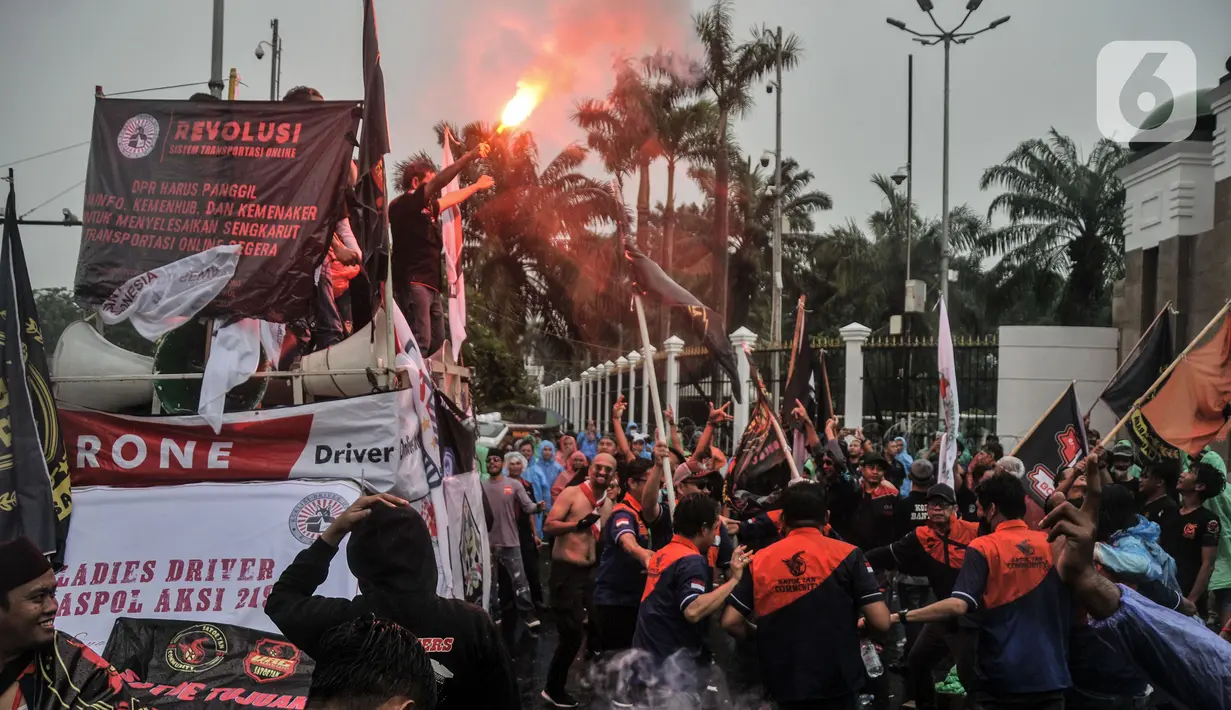 Pengemudi taksi dan ojek online menyalakan suar saat menggelar aksi di depan Gedung DPR RI, Jakarta, Rabu (21/9/2022). Puluhan massa tersebut menuntut pemerintah membuat payung hukum bagi mitra pengemudi online, menaikkan tarif dasar, menyetarakan potongan menjadi 10 persen, dan meminta subsidi asuransi kesehatan. (merdeka.com/Iqbal S. Nugroho)