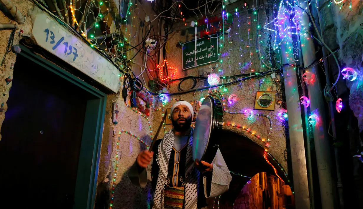 Michel Ayoub, seorang Kristen Arab-Israel, menabuh drum ketika membangunkan kaum muslim untuk sahur di Arce, Israel, Senin (20/6). Michel Ayoub sudah bertahun-tahun membangunkan kaum muslim di sekitarnya untuk sahur selama Ramadan. (REUTERS/Ammar Awad)