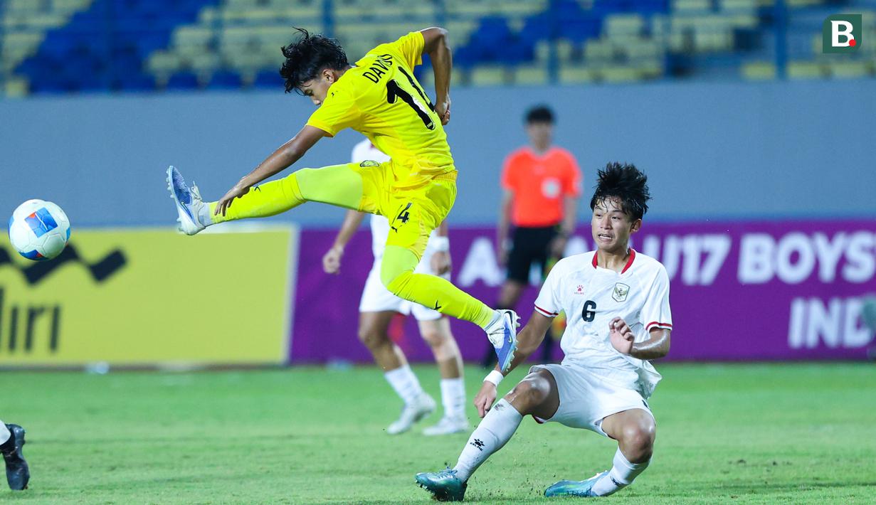 Pemain Timnas Malaysia, Dawud lmran Bin Rozlin, menendang bola saat berebut bola dengan Timnas Indonesia U-17, Girly Andrade Guevara, pada laga kedua Grup A Piala AFF U-17 2026 di Stadion Gelora Joko Samudro, Gresik, Jawa Timur, Kamis (16/4/2026) malam. (Bola.com/M Iqbal Ichsan)
