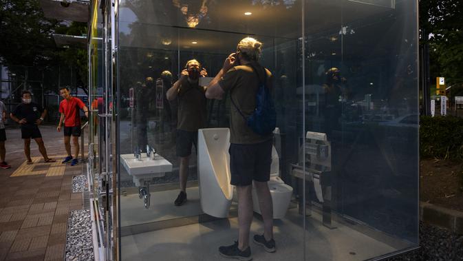 Seorang pria menggunakan toilet transparan di Haru-no-Ogawa Community Park di distrik Shibuya, Tokyo (19/8/2020). Toilet ini dirancang oleh arsitek Shigeru Ban dimana dinding luar kacanya akan berubah menjadi buram ketika kuncinya ditutup. (AFP Photo/Philip Fong)