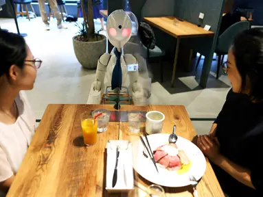 Robot humanoid mengantarkan minuman kepada pelanggan di Dawn Cafe, Tokyo, Jepang, 17 Agustus 2021. Peluncuran kafe ini bersamaan dengan Paralimpiade yang akan dibuka pada 24 Agustus. (Behrouz MEHRI/AFP)