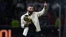 Pemain Real Madrid Karim Benzema berpose di lapangan dengan trofi Ballon d'Or miliknya pada paruh waktu pertandingan sepak bola L1 Prancis antara Olympique Lyonnais (OL) dan OGC Nice di Stadion Groupama, Decines-Charpieu, Prancis, 11 November 2022. Ia memperkuat Lyon senior sejak 2005 silam. (OLIVIER CHASSIGNOLE/AFP)