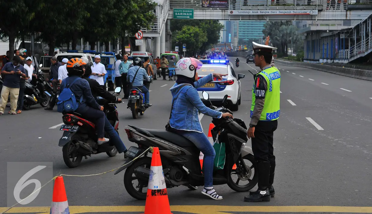 Seorang petugas polisi memberi petunjuk kepada pengendara motor saat pengalihan arus arus di kawasan Sarinah, Jakarta, Jumat (4/11). Pengalihan ini dilakukan karena beberapa titik jalan tidak bisa digunakan akibat aksi massa. (Liputan6.com/Angga Yuniar)