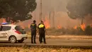Polisi dan petugas sipil melihat kebakaran hutan di dekat Mazagon di Spanyol selatan, Minggu (25/6). Sekitar 1.500 orang telah dievakuasi dari rumah, tempat perkemahan dan hotel menyusul kebakaran hutan tersebut. (AP Photo/Alberto Diaz)