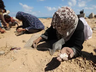 Para perempuan Palestina memungut kacang-kacangan atau beras di Nuseirat, Jalur Gaza tengah, usai misi penerjunan bantuan lewat udara di atas wilayah Palestina yang dikepung Israel pada 5 Agustus 2025. (Eyad BABA/AFP)