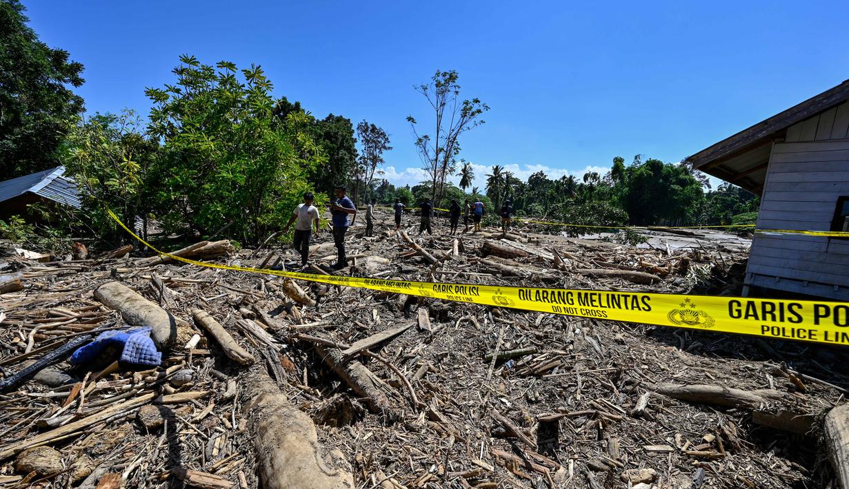 Pemerintah Kabupaten Pidie Jaya, Aceh, mendata hingga Minggu 30 November 2025, ada 20 orang meninggal dunia dan 18 lainnya masih hilang sejak banjir menerjang wilayah tersebut pada Rabu 26 November 2025. Tampak dalam foto, orang-orang berjalan melintasi lumpur dan puing-puing di daerah terdampak banjir di Meureudu, Kabupaten Pidie Jaya, Provinsi Aceh, pada 30 November 2025. (CHAIDEER MAHYUDDIN/AFP)