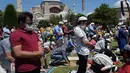 Umat Muslim berdoa saat menunaikan salat Jumat dengan latar belakang situs bersejarah Hagia Sophia di distrik bersejarah Sultanahmet di Istanbul, Jumat (24/7/2020). Hari ini, Hagia Sophia menyambut umat Islam melaksanakan salat Jumat pertama dalam 86 tahun.(AP Photo/Yasin Akgul)