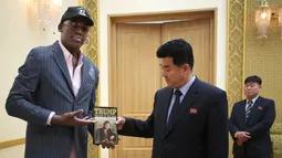 Mantan pemain Chicago Bulls, Dennis Rodman memberikan sebuah buku berjudul "Trump The Art Of The Deal" kepada menteri olahraga Korea Utara Kim Il Guk di Pyongyang, Korea Utara (15/6). (AP Photo/Kim Kwang Hyon)