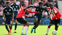 Gelandang Manchester United, Kobbie Mainoo mendapatkan himpitan dari dua pemain Southampton dalam lanjutan Premier League 2024/2025, Sabtu (14/9/2024). (AFP/Glyn Kirk)