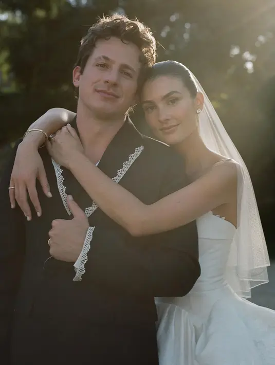 Keduanya tampil serasi dalam balutan busana pengantin. Charlie Puth mengenakan setelan hitam dengan atasan jas kasual dan aksen renda putih dibuat oleh Bode. Sementara itu, Brooke mengenakan gaun putih tube dengan teil panjang dan veil pendek di atas rambut sanggulnya karya Danielle Frankel Studio. (Liputan6.com/IG/@charlieputh)