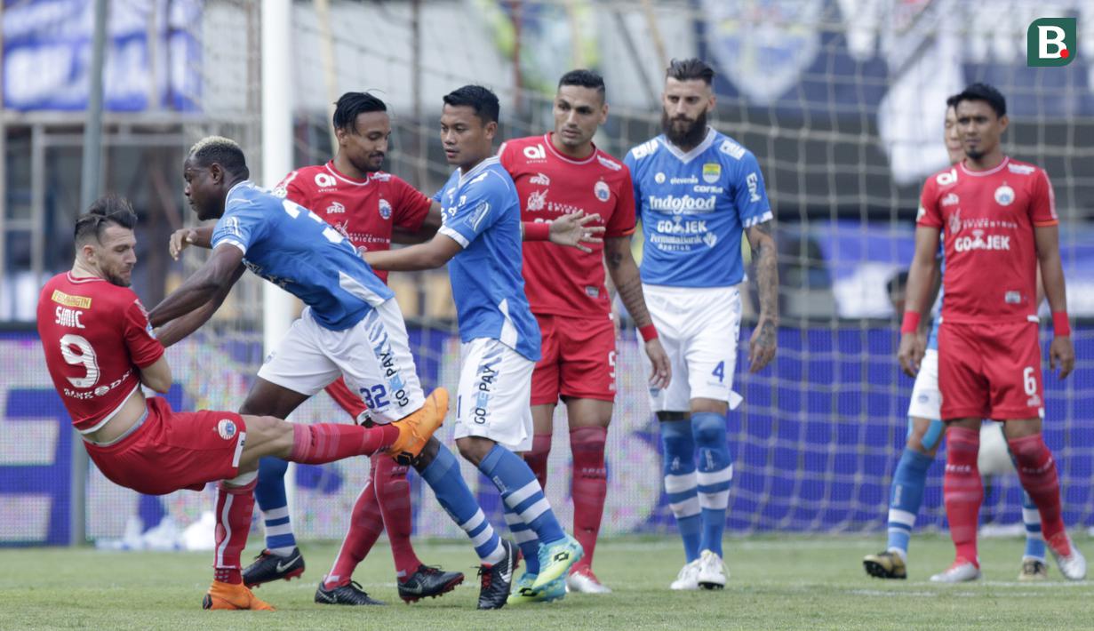 Striker Persija Jakarta, Marko Simic, terjatuh saat berebut bola dengan bek Persib Bandung, Victor Igbonefo, pada laga Liga 1 di Stadion GBLA, Jawa Barat, Minggu (23/9/2018). Persib menang 3-2 atas Persija. (Bola.com/M Iqbal Ichsan)