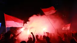 Mereka berkumpul merayakan kemenangan dengan mengibarkan bendera kebanggan Merah-Putih serta menyalakan suar sebagai bentuk rasa suka cita di dalam dunia sepak bola. (Bola.com/M Iqbal Ichsan)