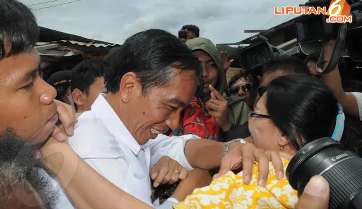 Seorang ibu tampak berusaha memeluk Jokowi namun tangan salah satu satgas berusaha menghalangi. Meski demikian, Jokowi tetap tersenyum (Liputan6.com/Herman Zakharia)