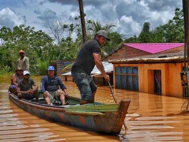 Orang-orang menaiki rakit di daerah yang terendam banjir setelah Sungai Acre meluap di Cobija, Bolivia, pada tanggal 29 Februari 2024. (STRINGER/AFP)