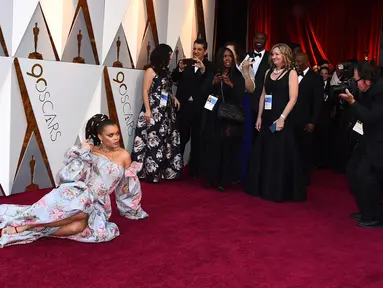 Penyanyi Andra Day berpose untuk fotografer sambil rebahan di karpet merah di penghargaan Piala Oscars 2018 di Dolby Theatre, Los Angeles, Minggu (4/3). Andra Day tampil glamor dalam balutan gaun off-shoulder bermotif floral. (Jordan Strauss/Invision/AP)