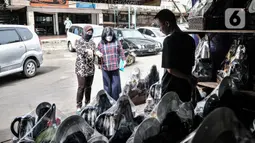 Pedagang parsel saat melayani pembeli di kawasan Cikini, Jakarta, Selasa (29/12/2020). Menurut salah satu pedagang, Dede (48), pandemi COVID-19 mengakibatkan penjualan parsel selama Natal dan jelang Tahun Baru merosot drastis dibandingkan tahun lalu. (merdeka.com/Iqbal S. Nugroho)
