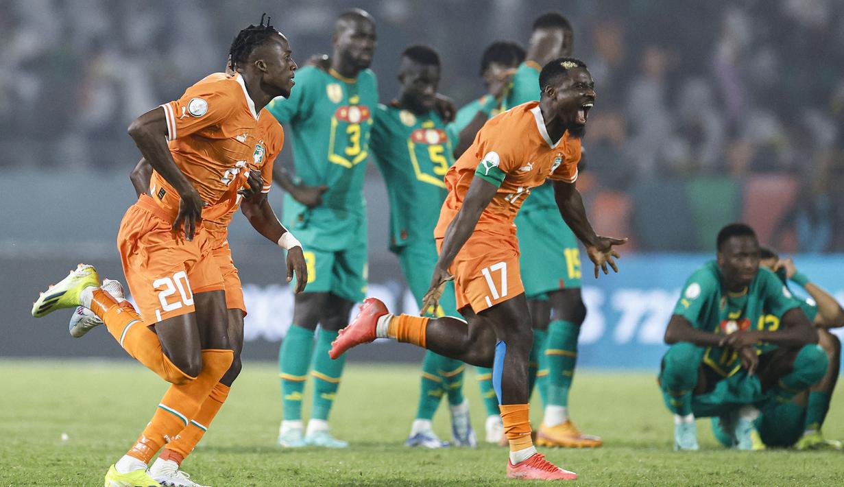 Sejumlah pemain Pantai Gading merayakan kemenangan atas Senegal pada babak 16 besar Piala Afrika 2023 di Stade Charles Konan Banny, Yamoussoukro, Selasa (30/01/2024) dini hari WIB. Pantai Gading menang dengan skor 5-4 pada babak adu penalti. (AFP/Kenzo Tribouillard)