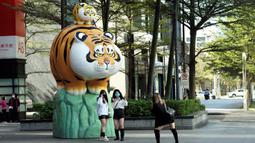 Warga berfoto dengan patung macan di depan pusat perbelanjaan jelang Tahun Baru Imlek di Taipei, Taiwan, 27 Januari 2022. Tahun Baru Imlek 2022 yang jatuh pada 1 Februari mendatang akan jadi tahun shio macan. (Sam Yeh/AFP)
