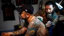Seorang seniman mentato badan pengunjung dalam acara edisi keempat Montreux Tattoo Convention di Montreux, Swiss  (22/9). Montreux Tattoo Convention berlangsung selama tiga hari. (Valentin Flauraud/Keystone via AP)