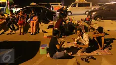 Sejumlah pemudik tengah beristirahat sambil menikmati makanan yang dijajakan pedagang di pinggir Tol Cikopo, Jawa Barat, Jumat (1/7). Kemacetan di sepanjang jalur tersebut dimanfaatkan pedagang untuk berjualan di sekitar lokasi (Liputan6.com/Angga Yuniar)