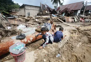 Hingga kini, tim gabungan dari BPBD, TNI, Polri, Basarnas, dan relawan terus melakukan pencarian terhadap warga yang masih hilang. Tampak dalam foto, anak-anak bermain di dekat rumah-rumah yang rusak di sebuah desa yang terdampak banjir bandang di Batang Toru, Sumatera Utara, Senin 1 Desember 2025. (AP Photo/Binsar Bakkara)