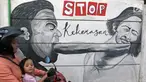 Pengendara sepeda motor melintas di sisi tembok yang terdapat lukisan mural di kawasan Kramat Jati, Jakarta, Rabu (4/4). Kawasan ini mendapat julukan Kampung Mural. (Liputan6.com/Herman Zakharia)