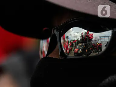 Aksi unjuk rasa buruh terefleksi dari kacamata massa yang menggeruduk gedung DPR RI, Jakarta, Selasa (10/1/2023). Dalam aksinya mereka menyuarakan penolakan terhadap Peraturan Pemerintah Pengganti Undang-Undang (Perppu) Cipta Kerja karena dinilai telah mengkhianati konstitusi. (Liputan6.com/Faizal Fanani)